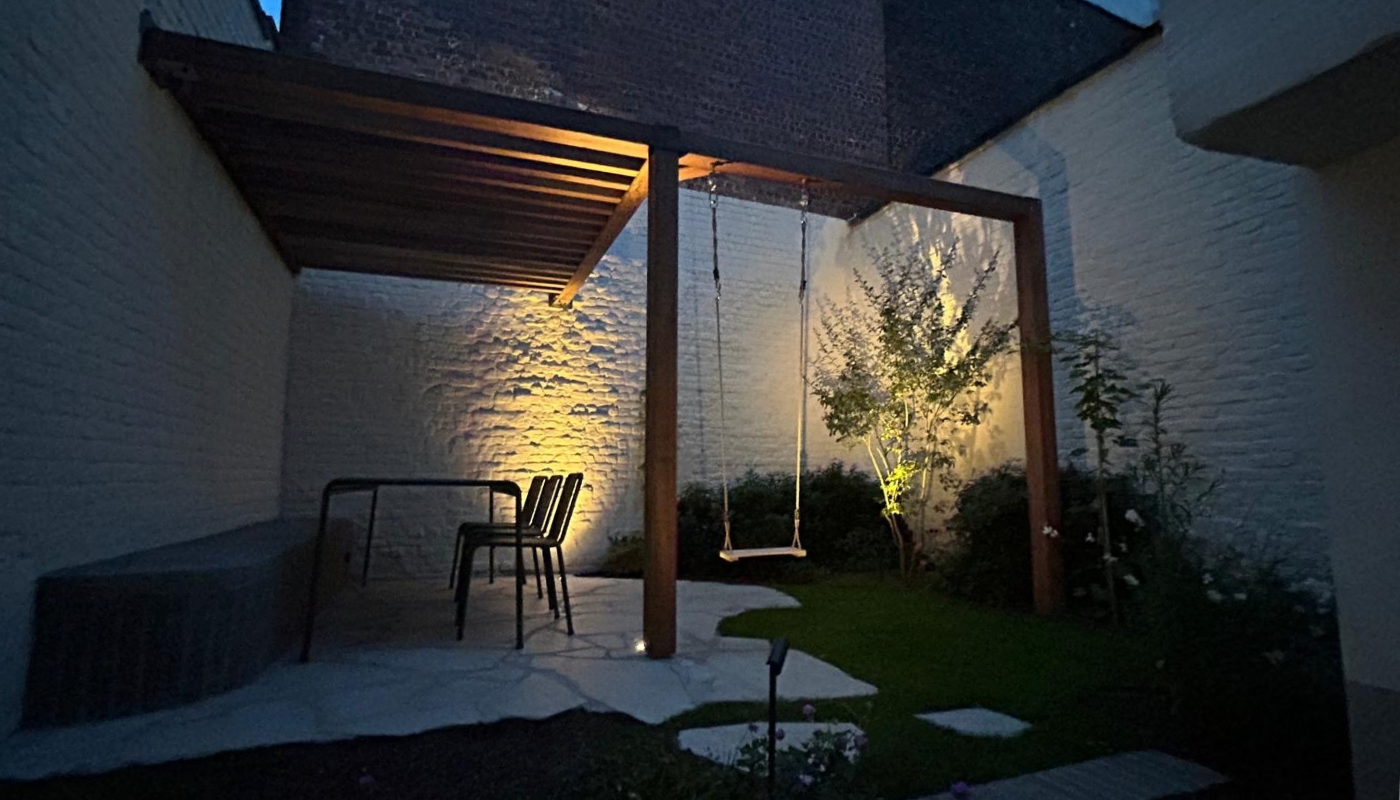 Houten terrasoverkapping met geïntegreerde schommel bij avond